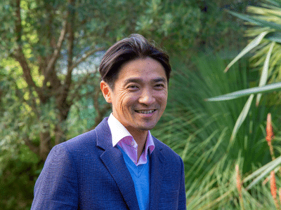 head shot of dennis lin with green bush in the background